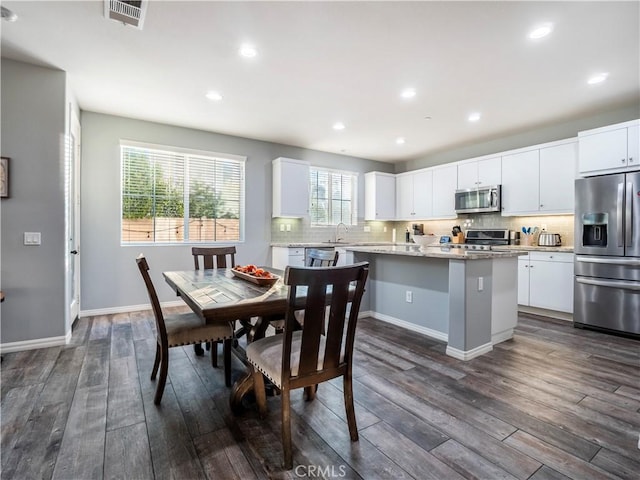 kitchen featuring white cabinets, dark wood-type flooring, stainless steel appliances, and a kitchen island