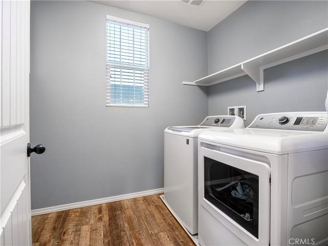 clothes washing area with washing machine and dryer and dark hardwood / wood-style floors