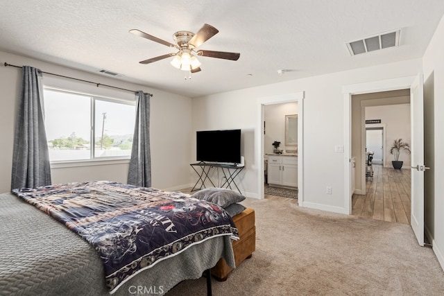 carpeted bedroom with ceiling fan, a textured ceiling, and ensuite bathroom