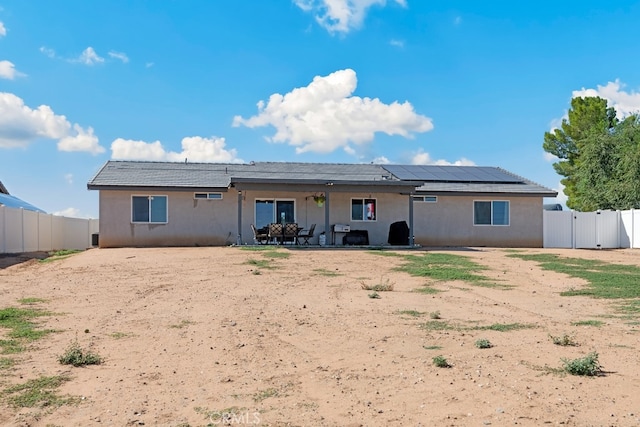 back of property featuring solar panels and a patio