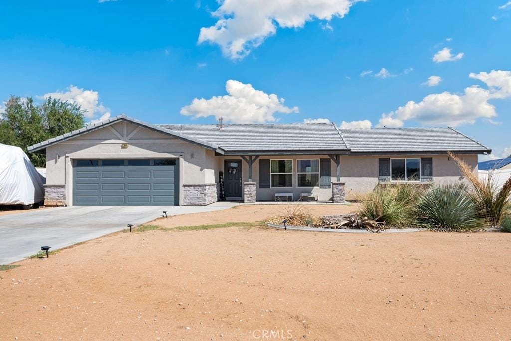 ranch-style home featuring a garage, stone siding, driveway, and stucco siding