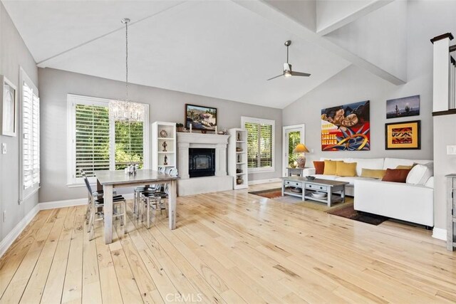 living room with ceiling fan with notable chandelier, light hardwood / wood-style flooring, high vaulted ceiling, and beamed ceiling