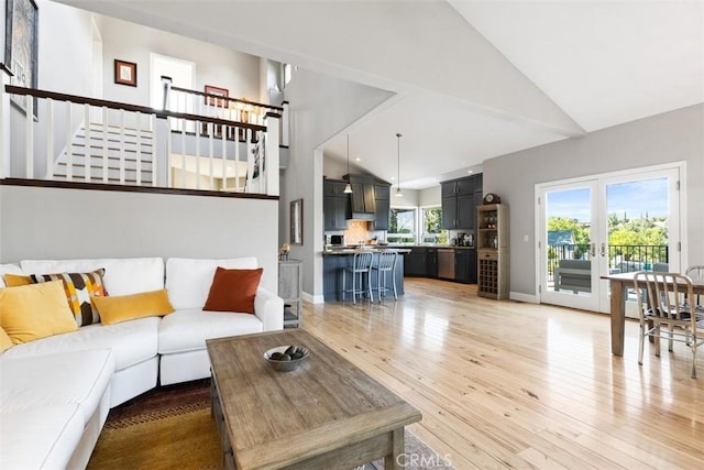 living room with a healthy amount of sunlight, high vaulted ceiling, and light hardwood / wood-style flooring