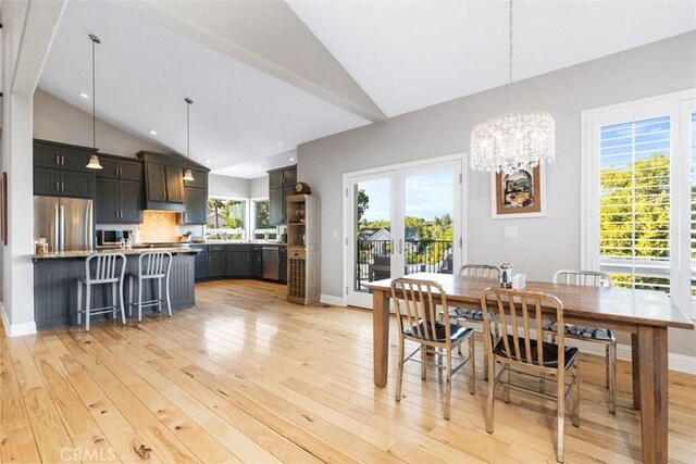 dining room with french doors, a wealth of natural light, high vaulted ceiling, and light hardwood / wood-style flooring