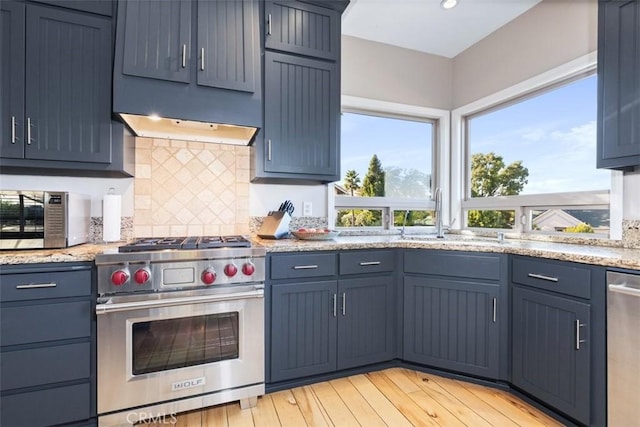 kitchen featuring blue cabinetry, appliances with stainless steel finishes, sink, and light hardwood / wood-style flooring