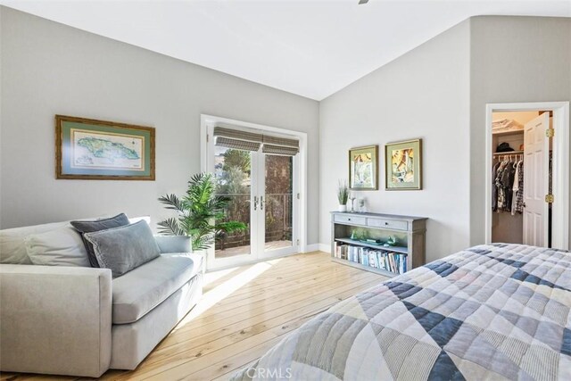 bedroom featuring lofted ceiling, light hardwood / wood-style flooring, access to exterior, a spacious closet, and french doors