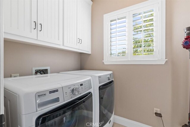 clothes washing area with cabinets and washing machine and clothes dryer