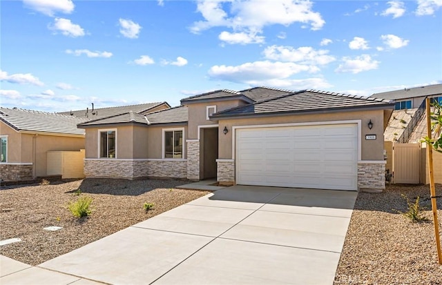 prairie-style house featuring stone siding, an attached garage, driveway, and stucco siding