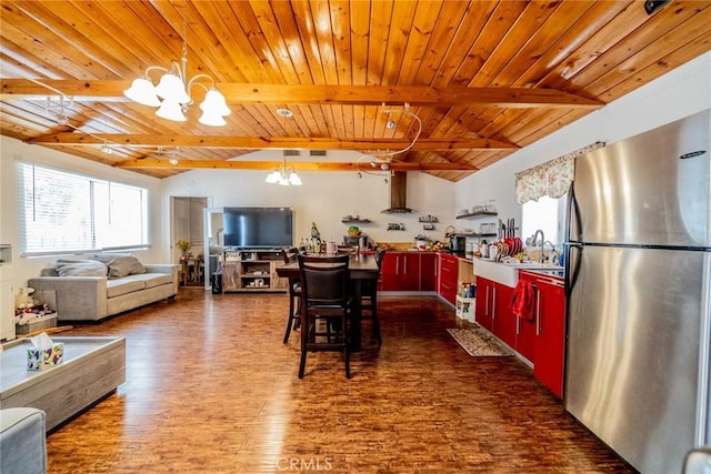 kitchen with wood ceiling, wall chimney exhaust hood, wood finished floors, freestanding refrigerator, and a notable chandelier