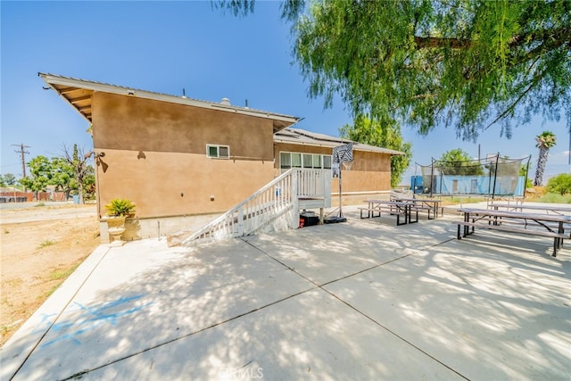 back of property featuring a trampoline and a patio area