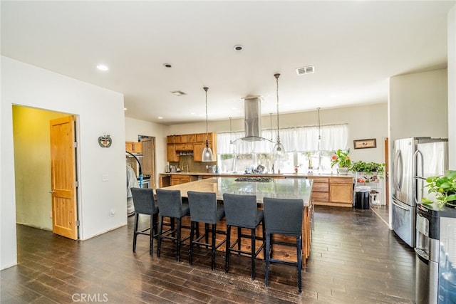 kitchen featuring island range hood, a center island, dark hardwood / wood-style floors, and decorative light fixtures