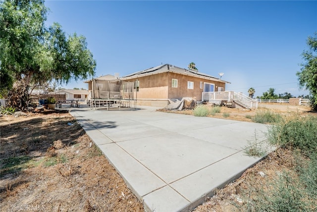 rear view of property featuring a trampoline and a patio area