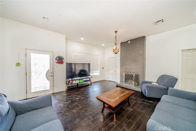 living room with a brick fireplace, an inviting chandelier, and dark hardwood / wood-style flooring