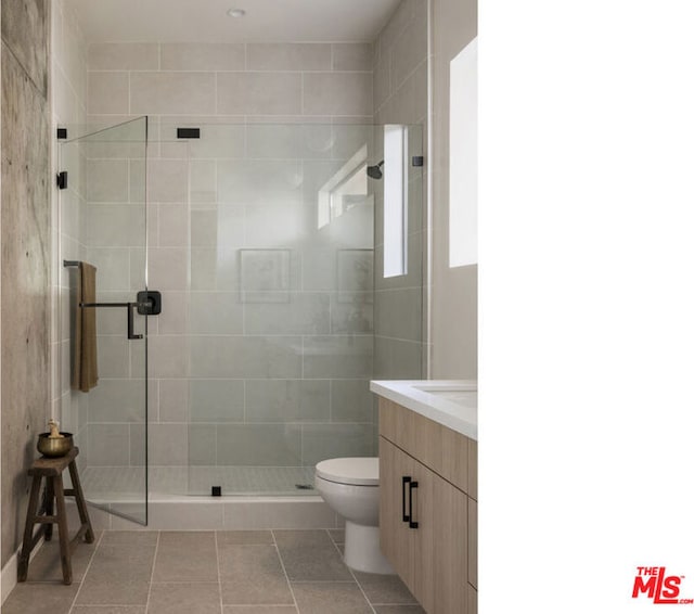 bathroom featuring walk in shower, tile patterned floors, toilet, vanity, and tile walls