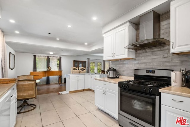 kitchen with dishwasher, wall chimney range hood, stainless steel range with gas cooktop, kitchen peninsula, and white cabinets