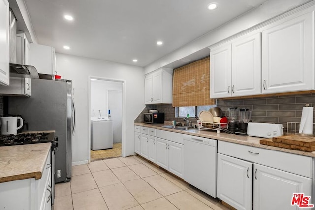 kitchen featuring white appliances, sink, light tile patterned flooring, white cabinetry, and washer / clothes dryer