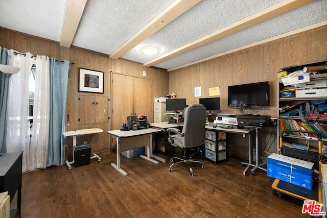 office space featuring beamed ceiling, a textured ceiling, dark wood-type flooring, and wood walls