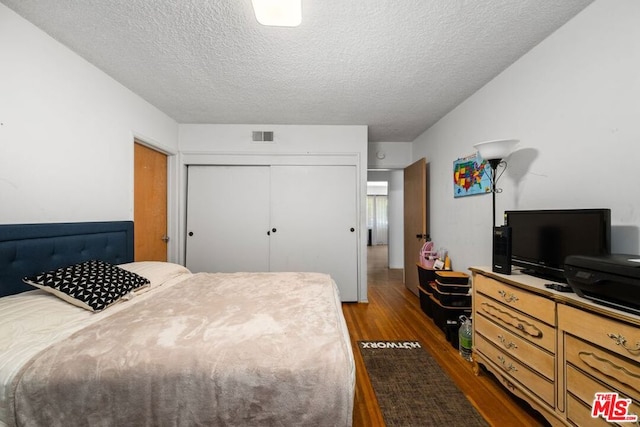 bedroom featuring a textured ceiling, a closet, and dark wood-type flooring