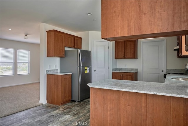 kitchen featuring dark hardwood / wood-style flooring, kitchen peninsula, stainless steel refrigerator, and range