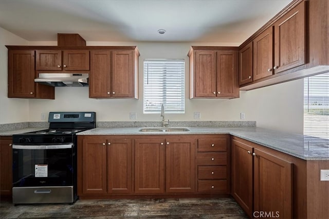 kitchen featuring stainless steel stove, light stone counters, dark hardwood / wood-style floors, and sink