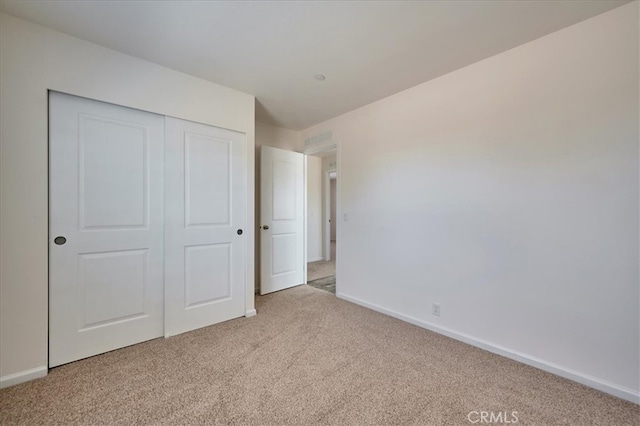 unfurnished bedroom with light carpet and a closet