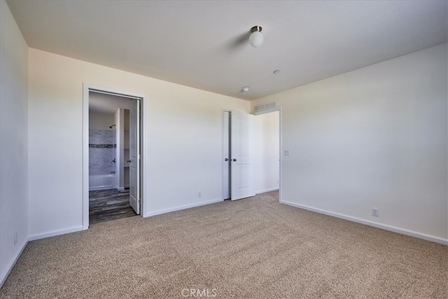 unfurnished bedroom featuring connected bathroom and carpet floors