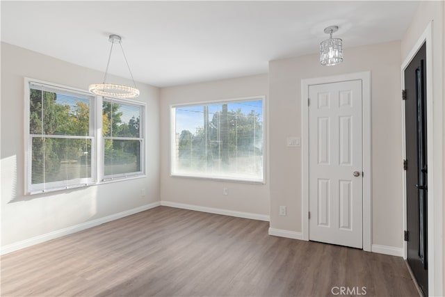 unfurnished dining area with hardwood / wood-style flooring and a chandelier