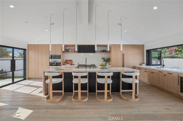 kitchen featuring high vaulted ceiling, a kitchen bar, a wealth of natural light, and a center island with sink