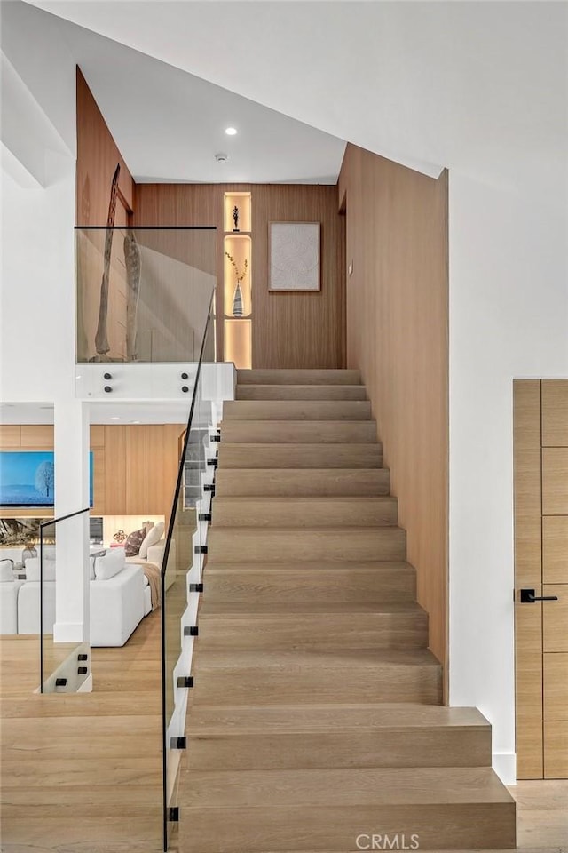 staircase with hardwood / wood-style floors and wood walls