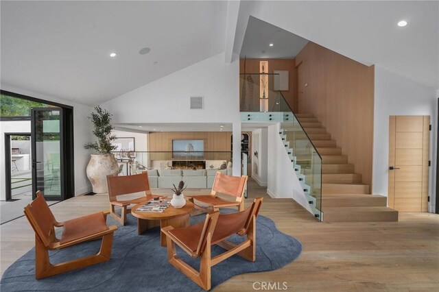 living room with high vaulted ceiling, light hardwood / wood-style flooring, and beamed ceiling