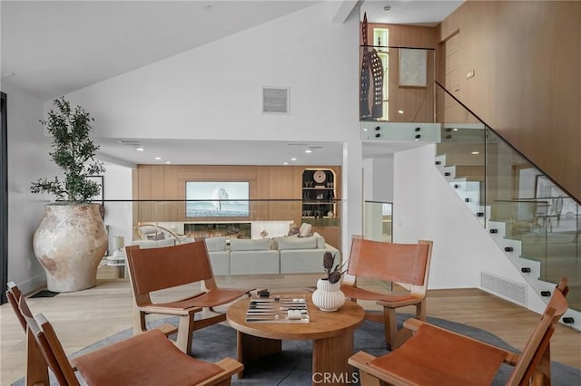 dining area with high vaulted ceiling and light hardwood / wood-style floors