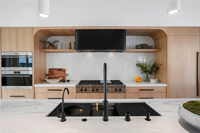 kitchen with exhaust hood, multiple ovens, light brown cabinetry, and light stone counters