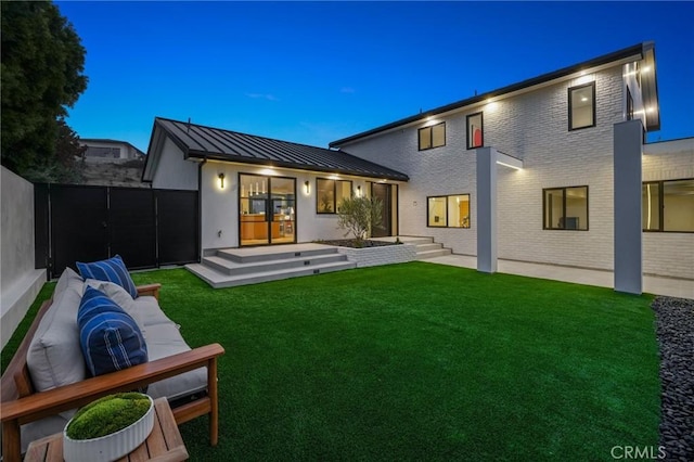 back house at dusk with outdoor lounge area and a yard