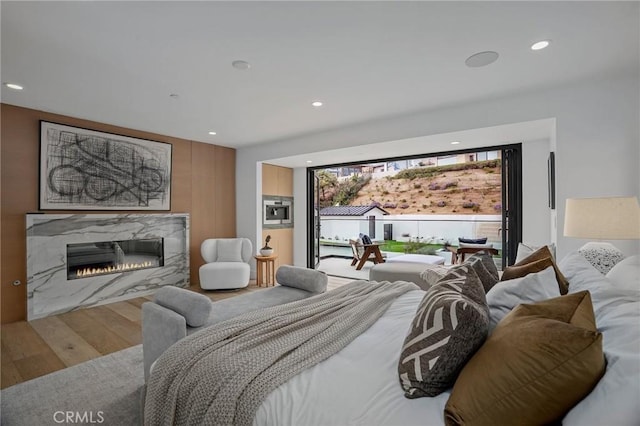 bedroom with a high end fireplace and hardwood / wood-style floors