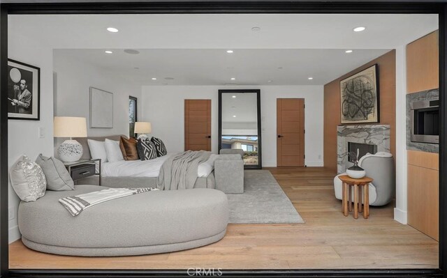 bedroom with light wood-type flooring and a fireplace