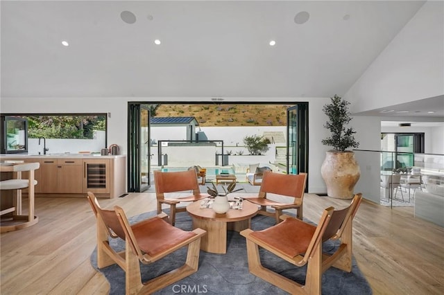 sitting room with light hardwood / wood-style floors, sink, lofted ceiling, and wine cooler