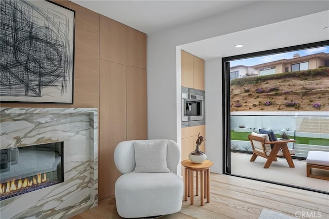 living area with a high end fireplace and light hardwood / wood-style flooring