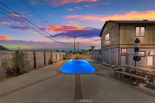 pool at dusk with a patio area