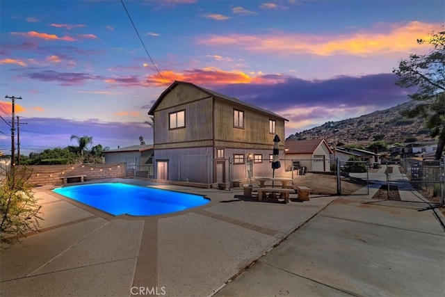 pool at dusk featuring a mountain view, a patio, and a fire pit