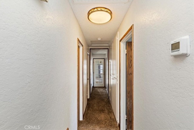 hallway featuring carpet and a textured ceiling