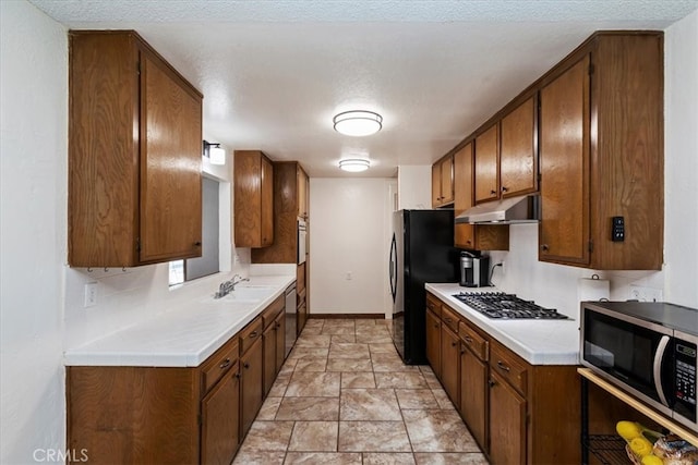 kitchen with a textured ceiling, appliances with stainless steel finishes, sink, and decorative backsplash