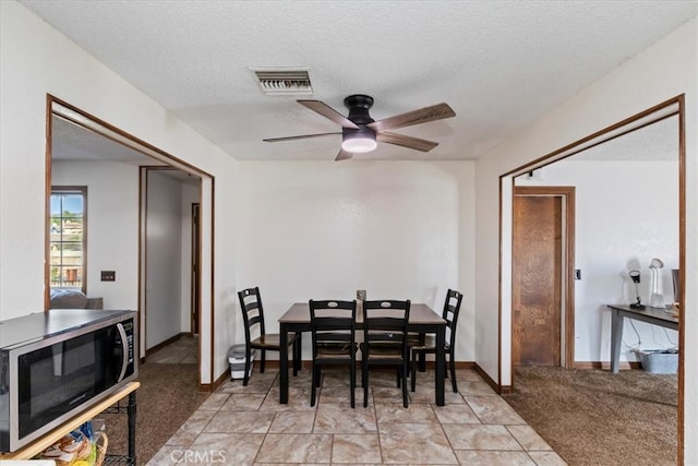 carpeted dining area with ceiling fan and a textured ceiling