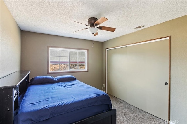 bedroom with a closet, ceiling fan, carpet, and a textured ceiling