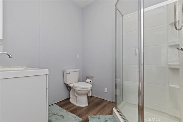 bathroom featuring vanity, hardwood / wood-style floors, toilet, and a shower with door