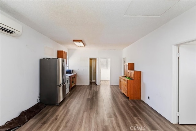 kitchen featuring a wall mounted AC, a textured ceiling, stainless steel refrigerator, and dark hardwood / wood-style flooring