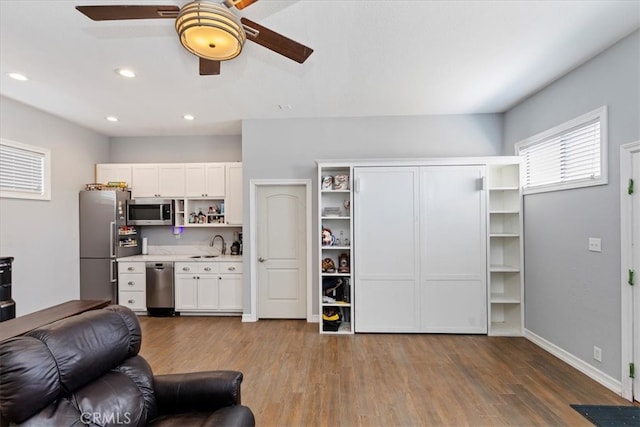 living room featuring sink, wood-type flooring, and ceiling fan