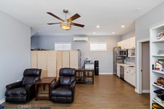 living area featuring an AC wall unit, sink, hardwood / wood-style floors, and ceiling fan