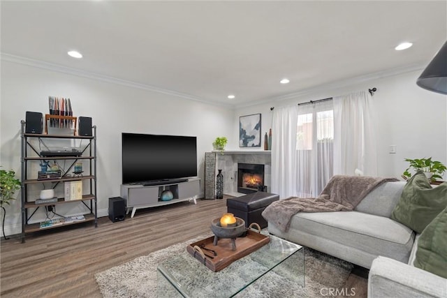 living room featuring wood-type flooring, ornamental molding, and a tile fireplace