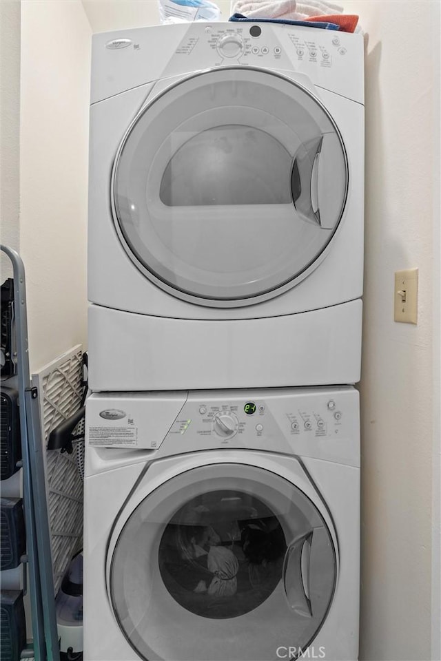 clothes washing area featuring stacked washer and clothes dryer