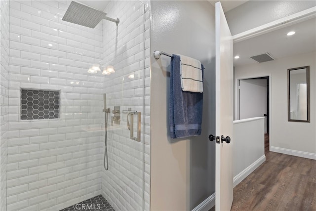 bathroom with a tile shower and hardwood / wood-style flooring